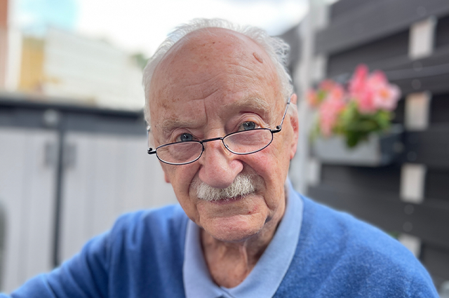 Älterer Mann mit Brille, Schnauzbart und blauem Oberteil